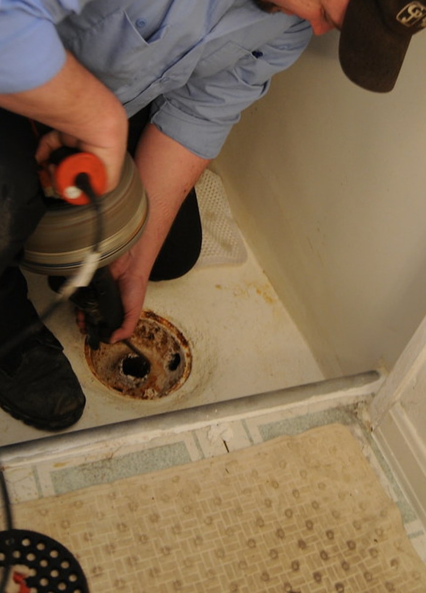 Engineer clearing a blocked drain with a professional drain snake