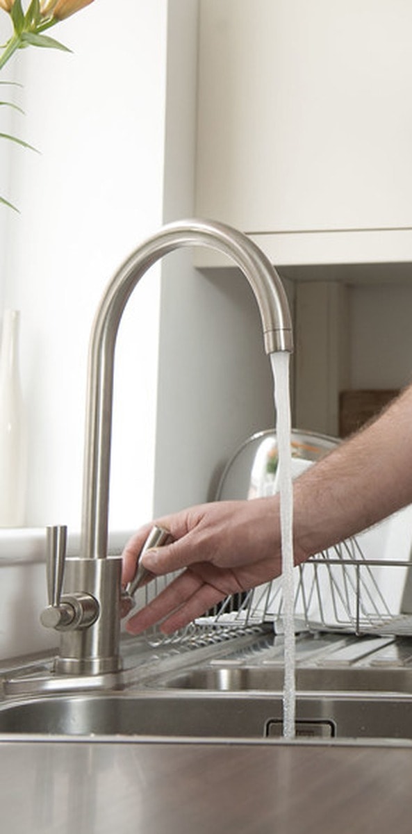 Engineer adjusting a modern kitchen mixer tap during a tap repair